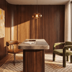 Clérachic amber glass pendant light glowing over a stone-topped desk in a walnut-panelled study with a leather chair.