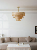 Seen from across a white room, a Clérachic leaf-glass pendant hangs above a taupe sofa and a lace-covered table.