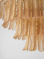 Close view of long, ribbed amber glass leaves layered in tiers on this Clérachic pendant, softly lit.