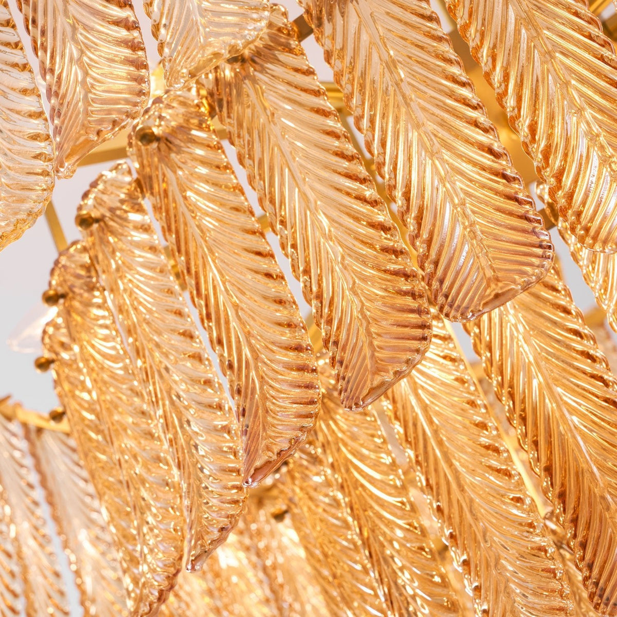 Close view of the veined amber glass leaves, overlapped and held on a brass frame, on this Clérachic pendant.
