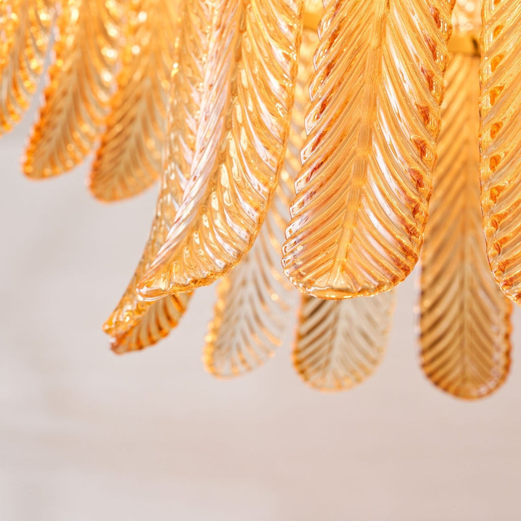 Close view of glowing amber glass leaves with fine ribbing, some clearer and some deeper in tone, on this Clérachic pendant.