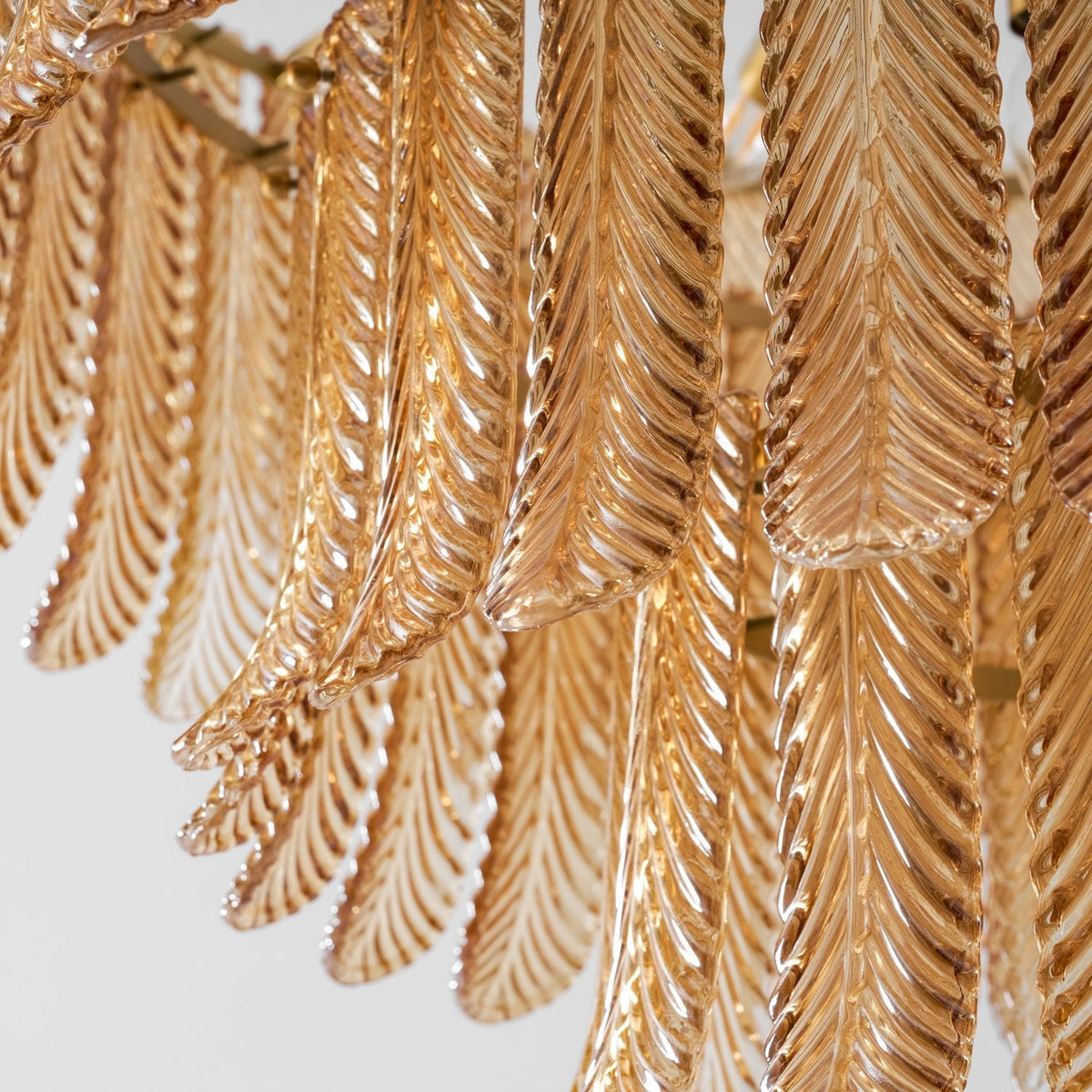 Close view from below of rows of ribbed amber glass leaves hanging in layers on this Clérachic pendant.
