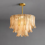 A Clérachic round pendant of pale amber glass leaves hangs from a short brass rod, shown unlit against grey.