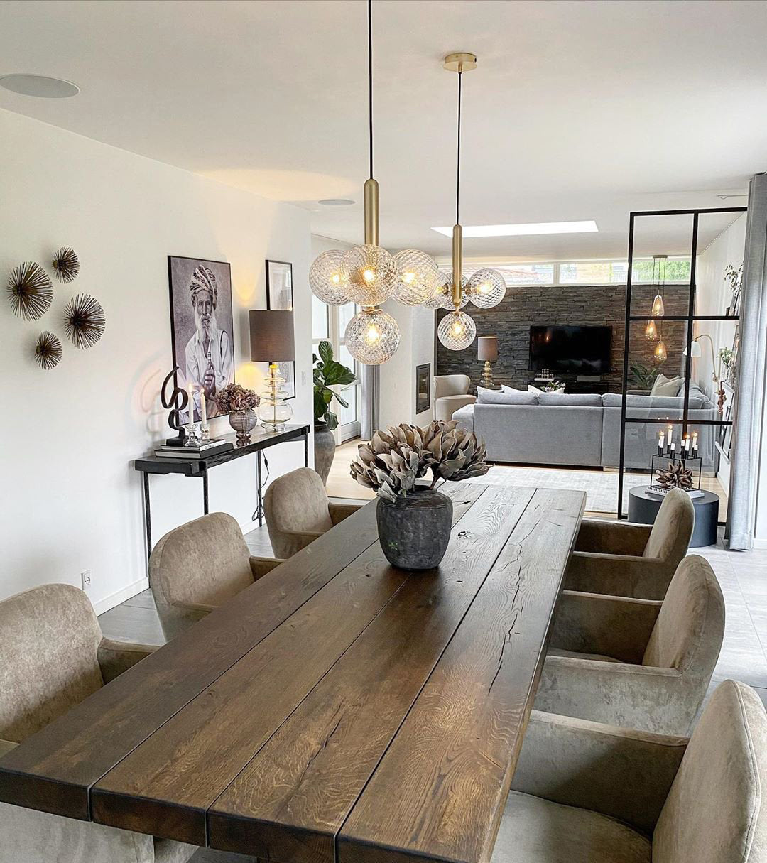 Clear glass cluster pendant from Clérachic above a long, rough-sawn oak dining table in an open-plan room.