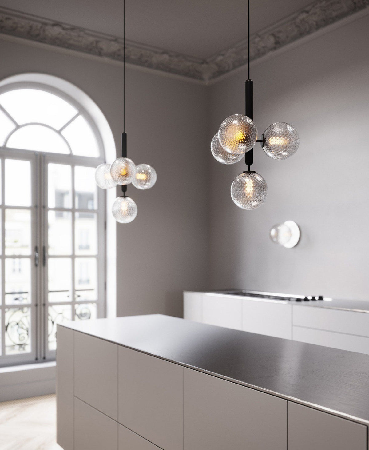 Two black-rod Clérachic cluster pendants with clear textured globes hang in a tall room with an arched window.