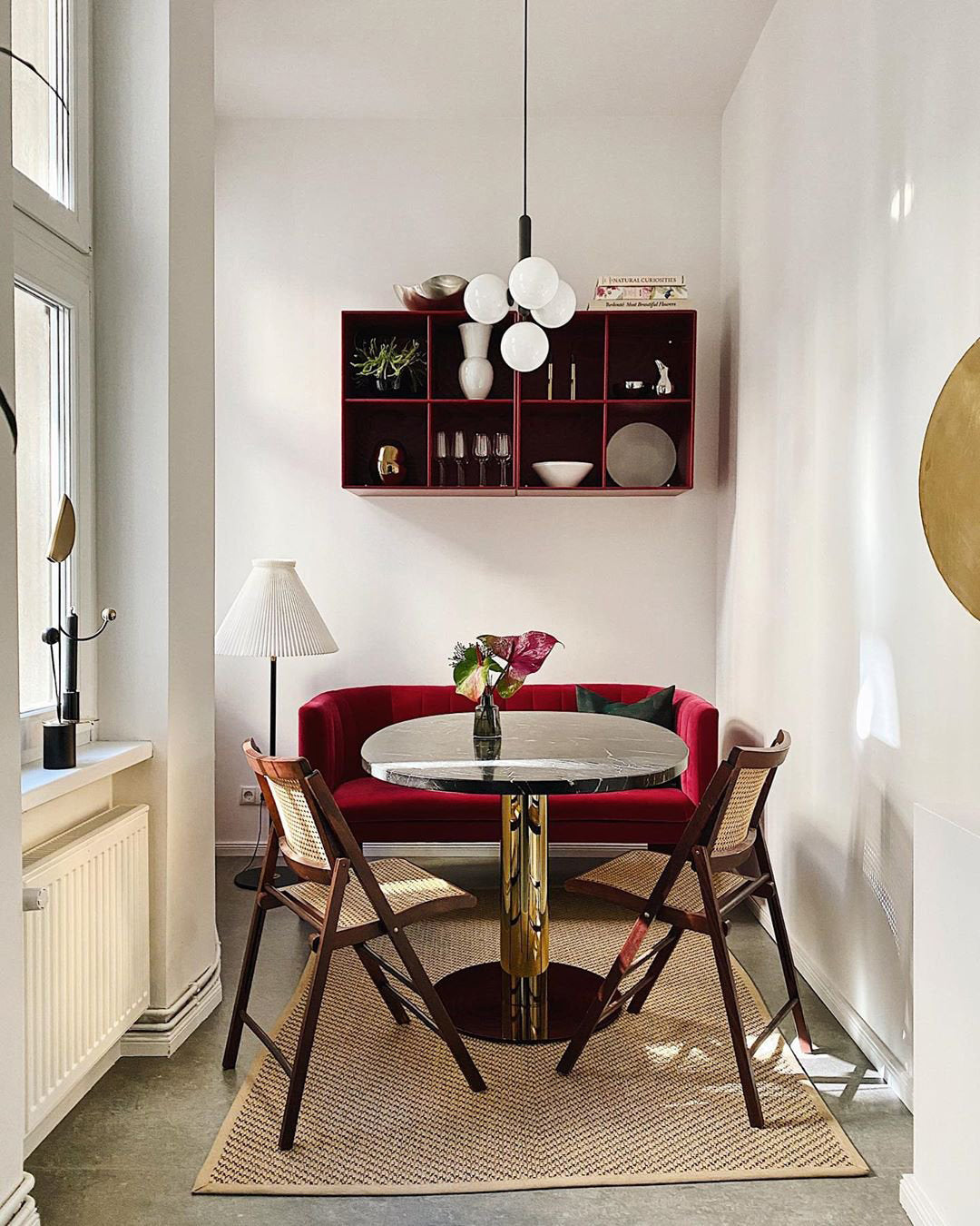 Clérachic pendant with white opal globes hangs in a corner dining nook with a red shelf and a red velvet bench.
