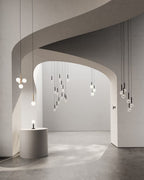 Tall stair-height drop of Clérachic pendants with white globes beside a curved wall, plus lamps on a stone plinth.