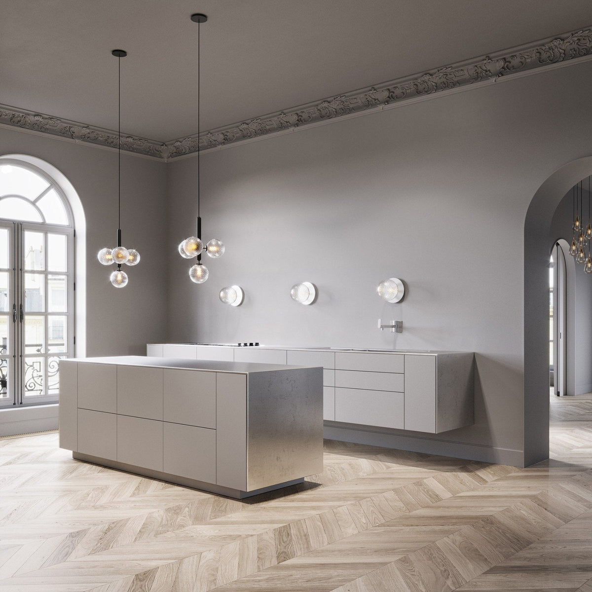 Two Clérachic cluster pendants with clear globes hang over a pale island in a room with arched doors and herringbone floor.