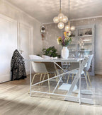 Two clear-glass Clérachic cluster pendants hang above a white table in a room with patterned wallpaper.