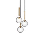 Three Clérachic pendants with clear textured globes on brass rods, hung close together on a white background.