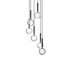 Seven Clérachic pendants with clear textured globes on black rods, cascading at different heights on white.