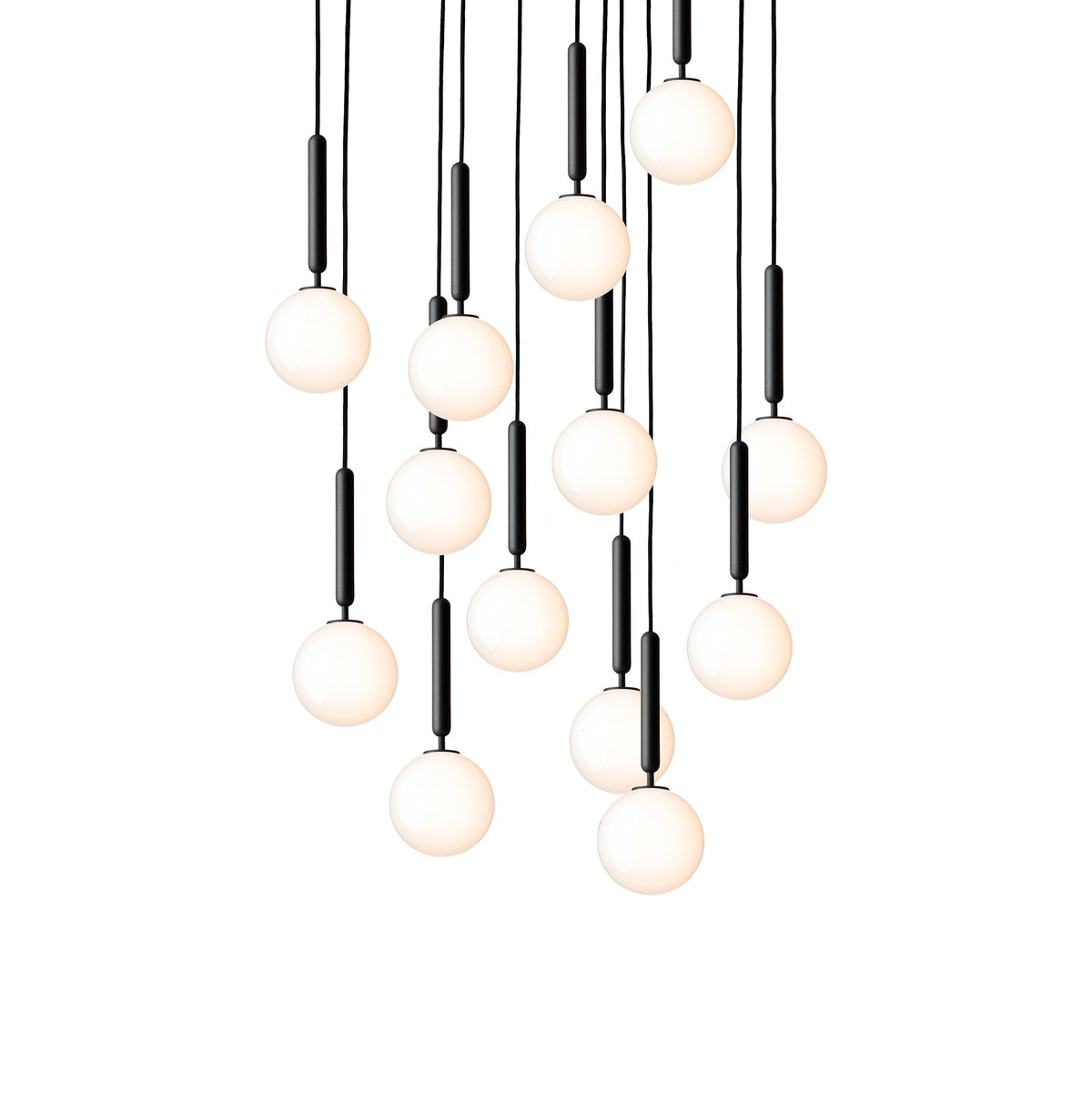 Clérachic pendants with white opal globes on black rods hang in a long cascade, lit warm on a white background.