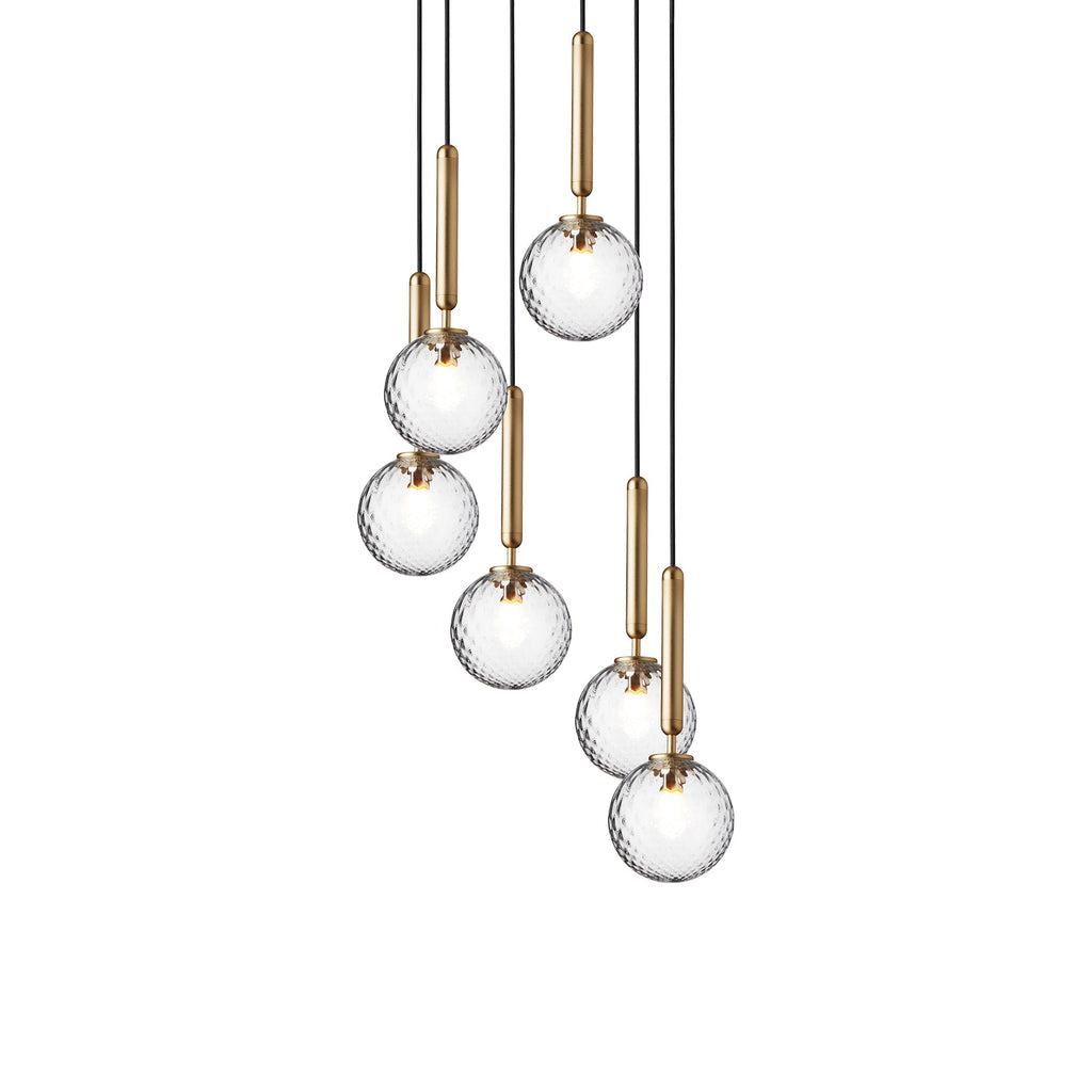 Eight Clérachic pendants with clear textured globes on brass rods hang at varied heights on a white background.