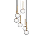 Eight Clérachic pendants with clear textured globes on brass rods hang at varied heights on a white background.