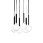 Six black-rod Clérachic pendants with white opal globes hang closely in a dense cluster on white.