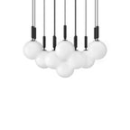 A wide, dense canopy of Clérachic pendants with white opal globes and black rods on a white background.