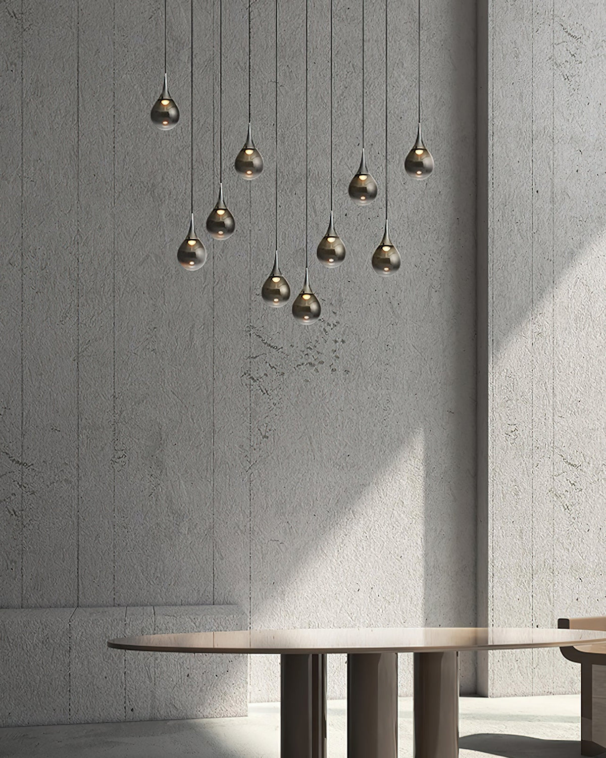 Smoked-glass Clérachic pendants hang at staggered heights against a rough grey concrete wall, above a round table.