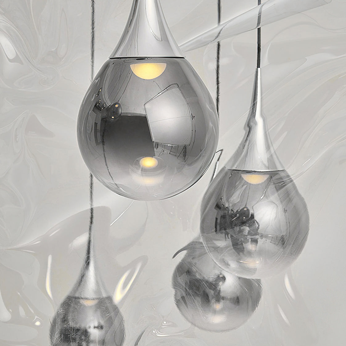 Close view of chrome-finish Clérachic pendants, their mirrored glass shades reflecting the room and a warm bulb inside each.