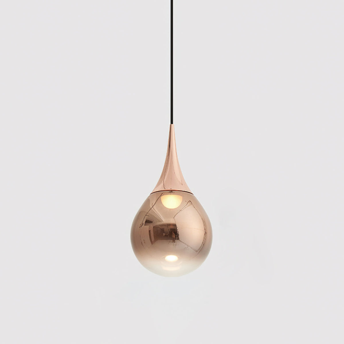 Rose gold Clérachic pendant with a polished teardrop shade, hanging from a black cord against a pale grey backdrop.