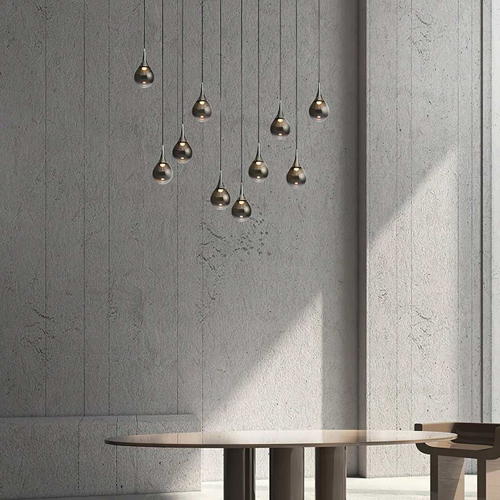 Smoke-toned Clérachic pendants in a loose cluster against a concrete wall, with a round wooden table below.