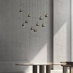 Smoke-toned Clérachic pendants in a loose cluster against a concrete wall, with a round wooden table below.