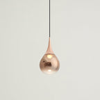 Rose gold Clérachic pendant with a copper shade fading to clear, set against a soft off-white wall.