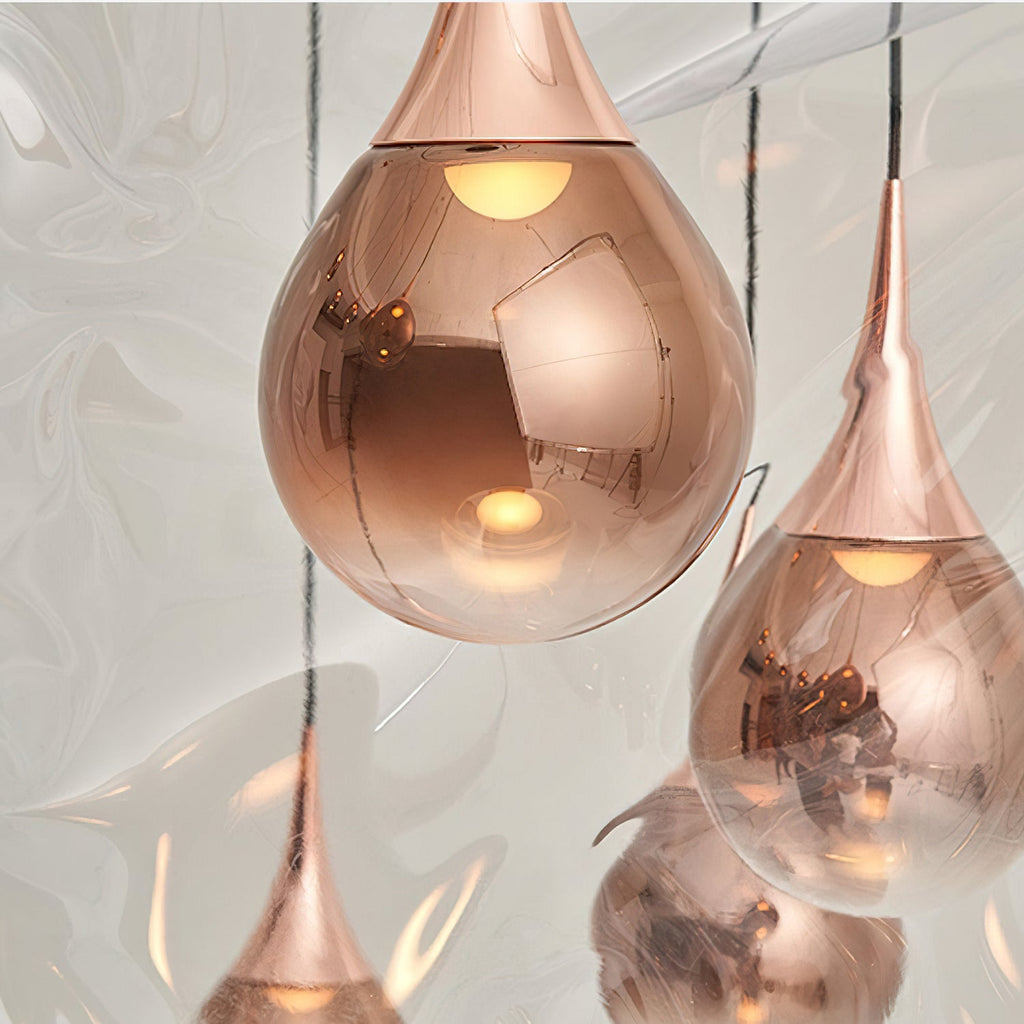 Close view of the polished rose gold shades and fittings on these Clérachic pendants, each with a warm bulb inside.