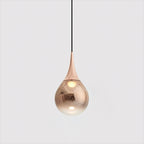 Rose gold Clérachic pendant with a copper-toned shade and a warm bulb visible within, on a light grey backdrop.