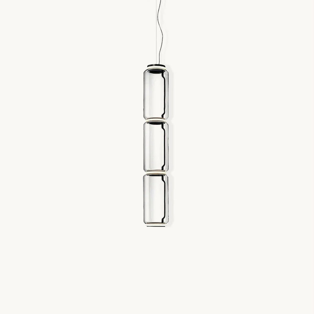 Three stacked clear glass cylinders with dark rings, this Clérachic pendant hanging on a thin cable against a plain white backdrop.
