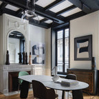 Glass dome from a Clérachic pendant at the top of the frame, over a curved table in a panelled room with a fireplace.