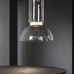 Close view of the glass dome and lit ring on this Clérachic pendant, with a round dark table below.