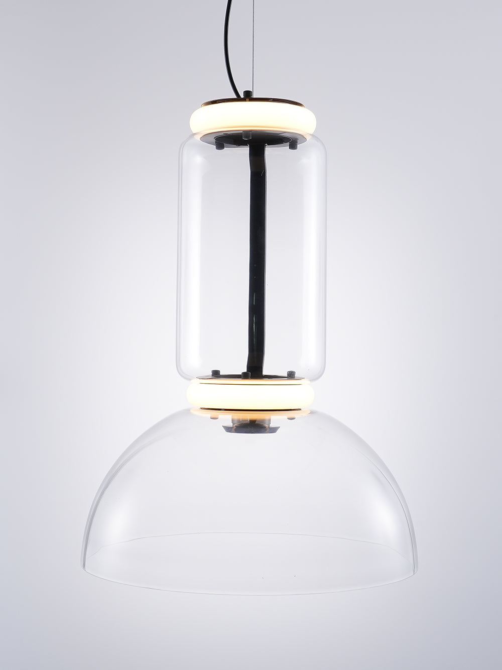 Glass cylinder with a lit ring above a clear dome, this Clérachic pendant on a pale grey backdrop with a black cable.