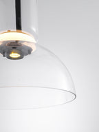 Close view of the glowing ring, the small light source and the edge of the clear glass dome on this Clérachic pendant.