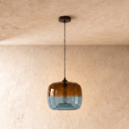 Clérachic amber-to-blue glass pendant switched off, showing the clear tubular bulb inside, on a black cord and canopy.