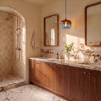 Clérachic amber and blue glass pendant lit above a marble vanity with walnut cabinets and a framed wooden mirror.