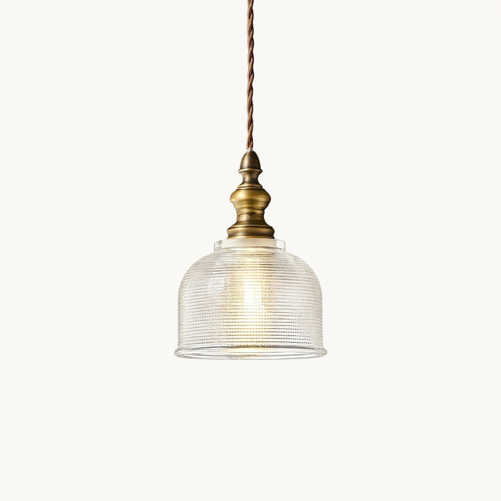 Pendant light from Clérachic with a ribbed clear glass dome, an antique brass fitting and a twisted fabric cord, on a plain white backdrop.