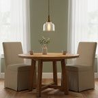Over a small round oak table set for two, this Clérachic glass pendant hangs against a sage green wall with sheer curtains.
