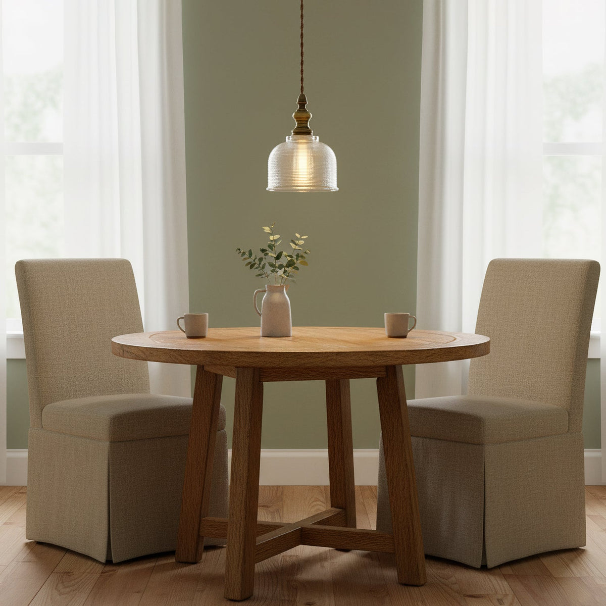 Over a small round oak table set for two, this Clérachic glass pendant hangs against a sage green wall with sheer curtains.