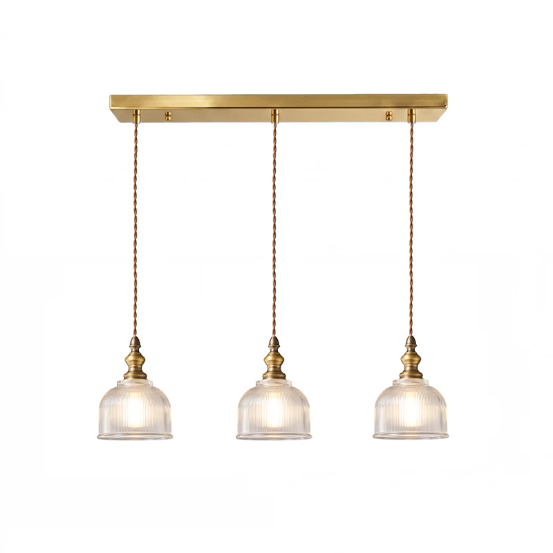 Three-light linear Clérachic pendant with ribbed glass domes on twisted cords, hung from a long brass canopy bar, on white.