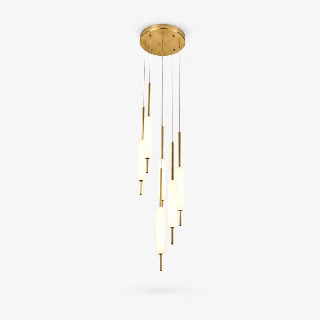 Cluster of slim brass-rod pendants with lit frosted glass cylinders from Clérachic, hung from a round brass canopy on a white backdrop.