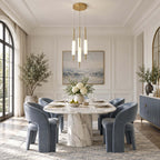 A round-canopy cluster of Clérachic frosted glass pendants hangs above an oval marble dining table with blue velvet chairs.