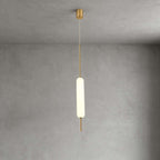 One lit Clérachic frosted glass pendant on a thin brass rod hangs from a small brass canopy against grey plaster.