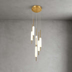 A cluster of Clérachic frosted glass pendants hangs from a round brass canopy against grey plaster, in a larger layout than the three-light.
