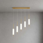 Five Clérachic frosted glass pendants step down in height from a long brass bar, lit against a grey plaster wall.