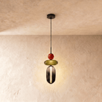 Clérachic pendant with a red bead, olive glass disc and smoked glass capsule below, lit on a slim black cord.