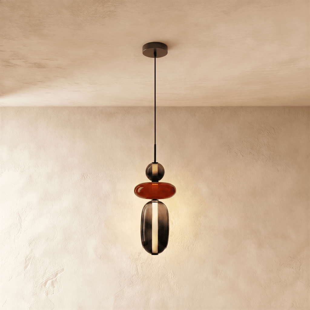 Clérachic pendant combining a smoked glass bead, a flat terracotta-red disc and a tall smoked capsule with a light strip.