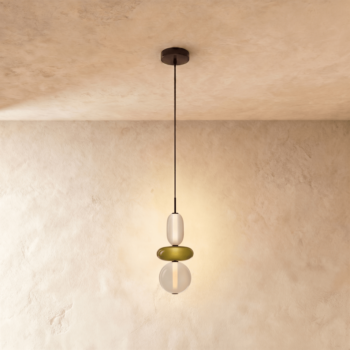 Clérachic short pendant with a frosted capsule, olive green glass disc and round opal globe, glowing against plaster.