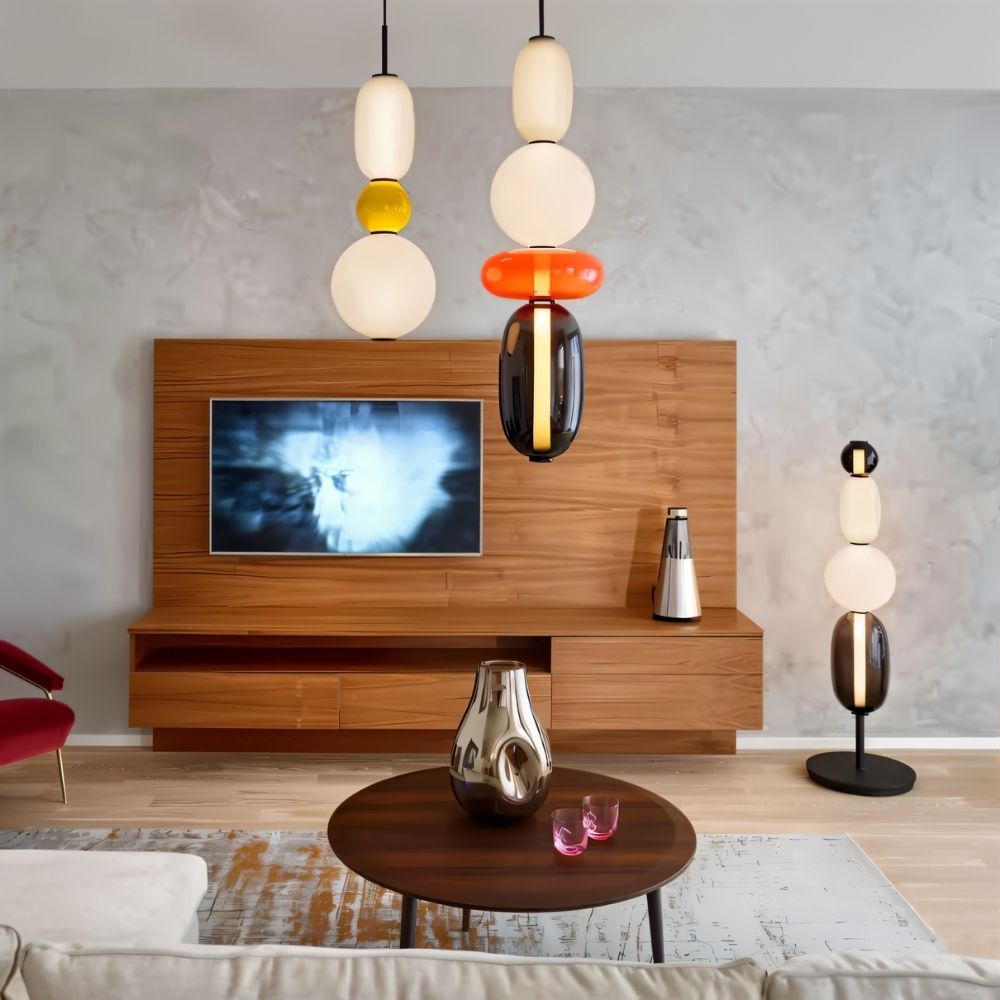 Clérachic glass pendants hanging in a living room beside a walnut media unit, with a matching floor lamp on the right.