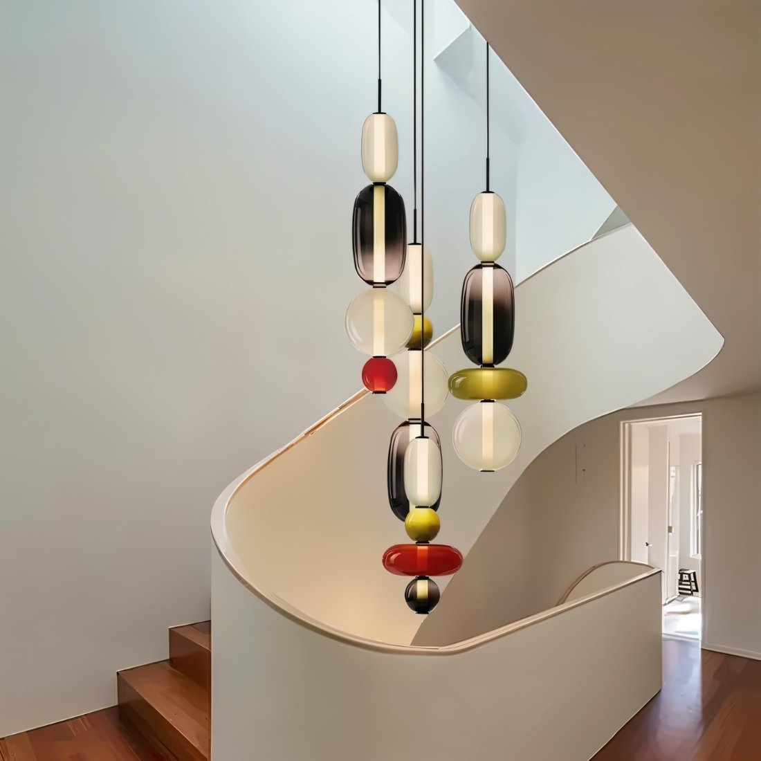 Clérachic glass pendants in a mix of colours cascading at different heights down a curved white staircase.