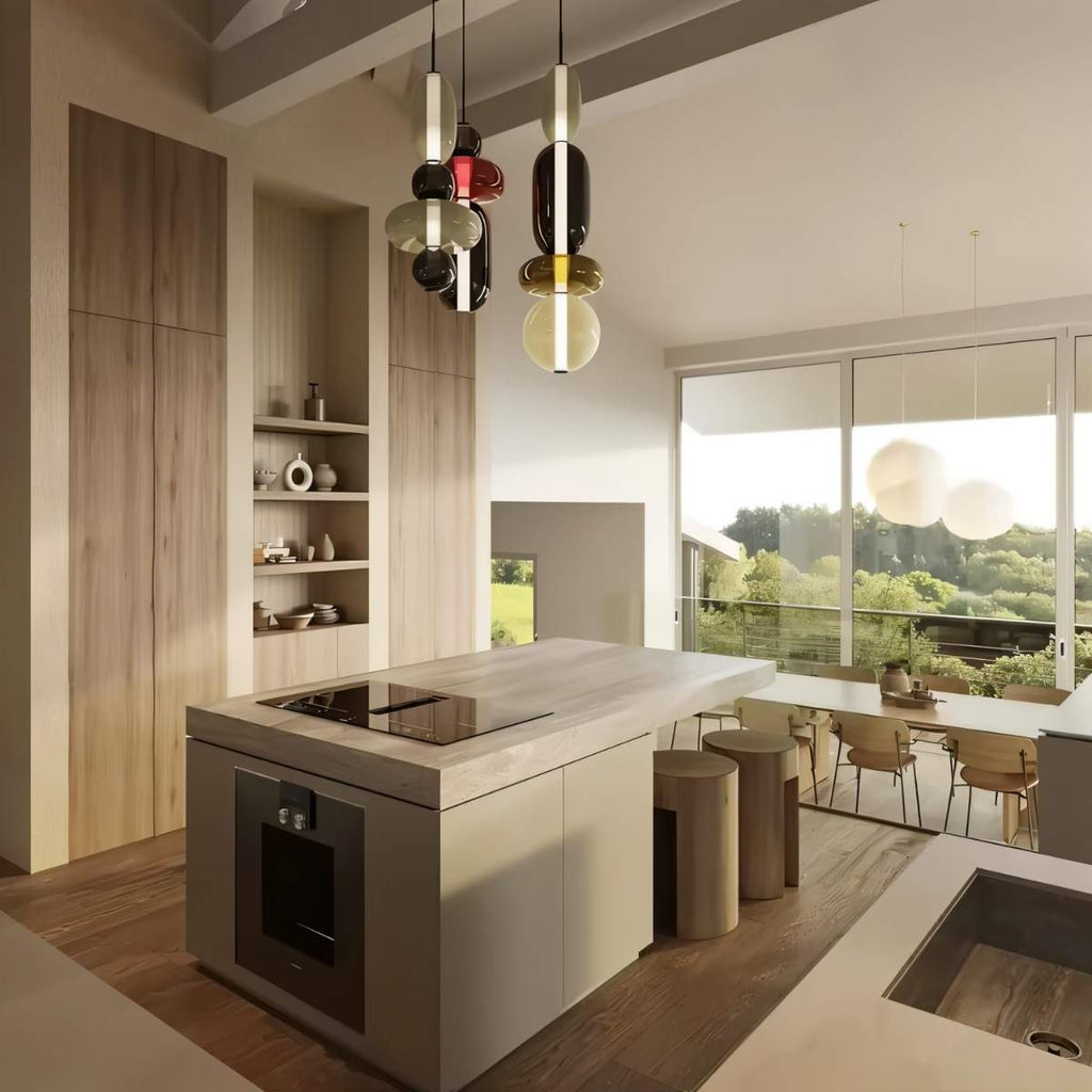 Clérachic coloured glass pendants hanging at varied heights over a kitchen island in a bright timber-clad open-plan room.